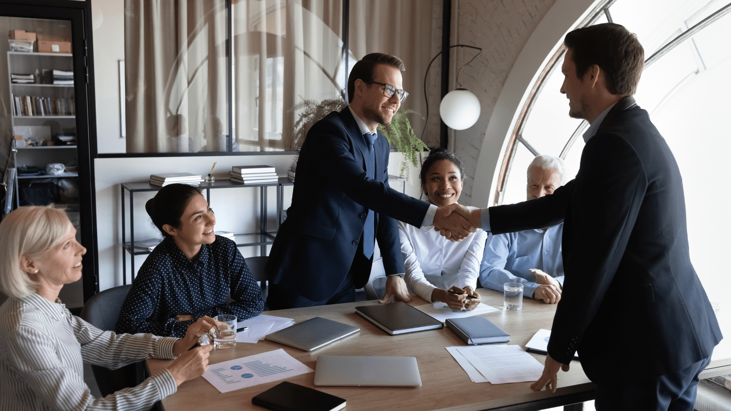2 executives shaking hands in a conference room setting