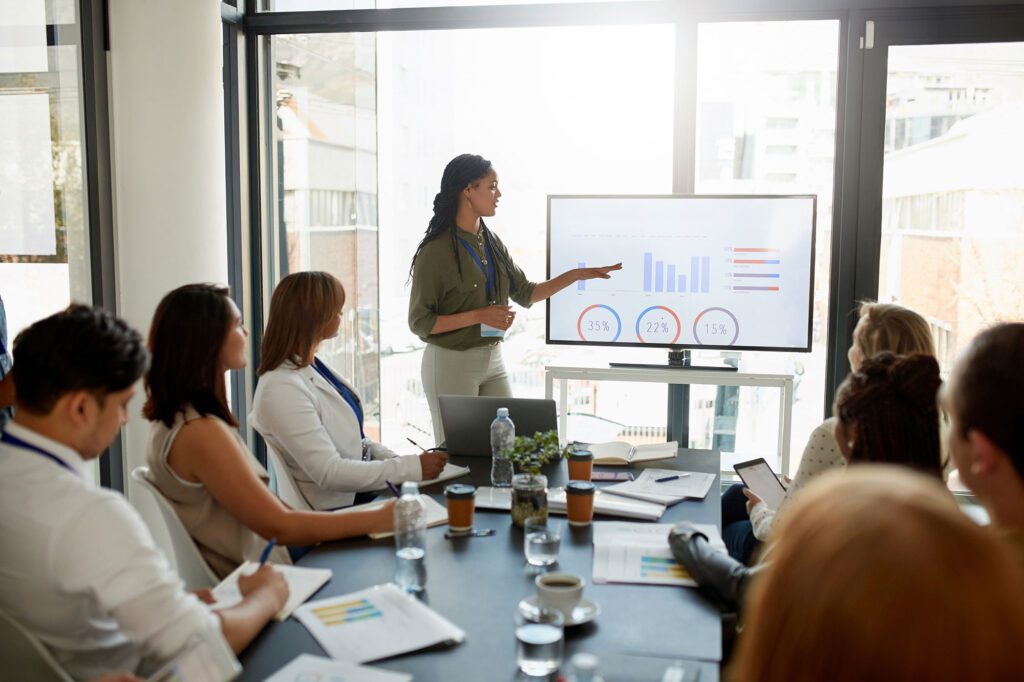 Woman presenting charts on a TV screen in a board room