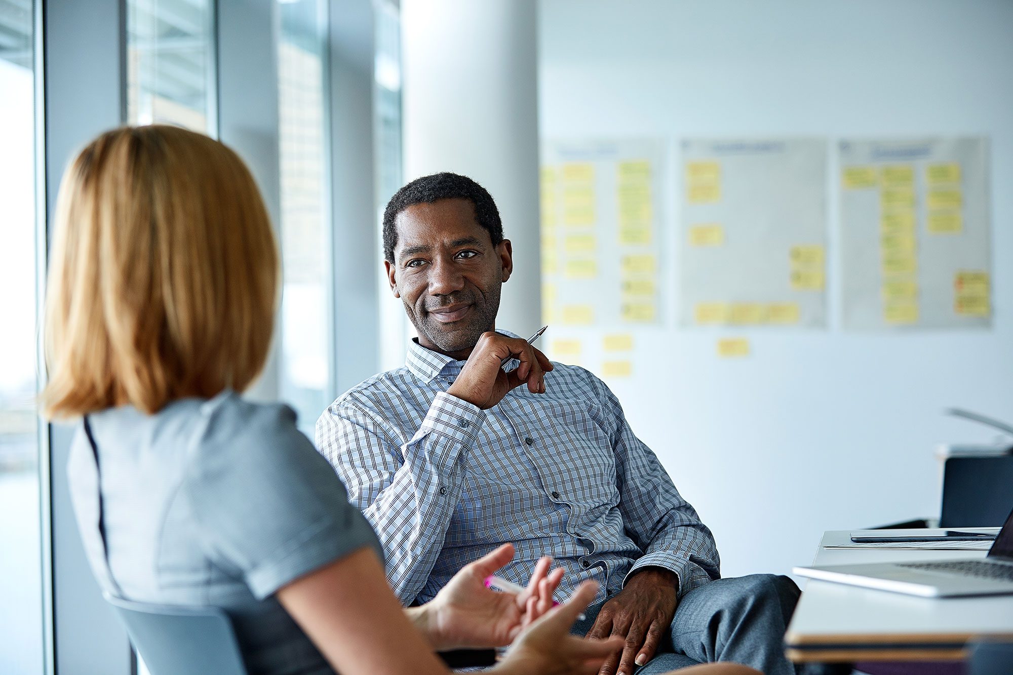 Man in colored shirt speaking with a woman at the office